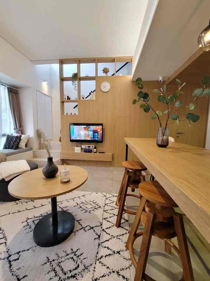 Compact living room with natural wood tones and white walls, featuring wooden bar stools and coffee table in a modern natural style