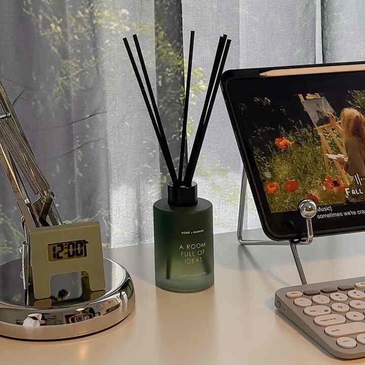 Natural toned home office space featuring a wood-tone diffuser and wireless keyboard on a white desk