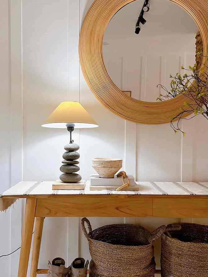 Minimal entrance space in wood tone and white, featuring a wooden console table with a lamp and art objects arranged harmoniously