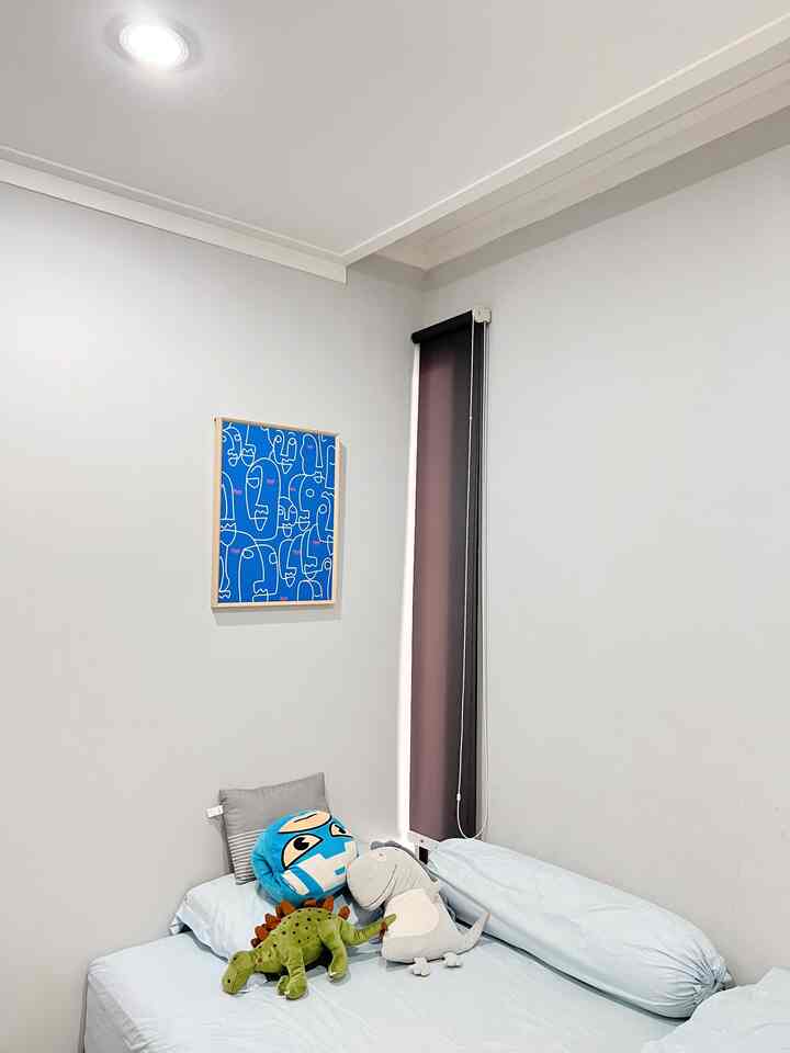 Pastel-toned kids' bedroom featuring a neat bed, black roller blind on narrow window, and abstract wall decor for a simple cozy atmosphere