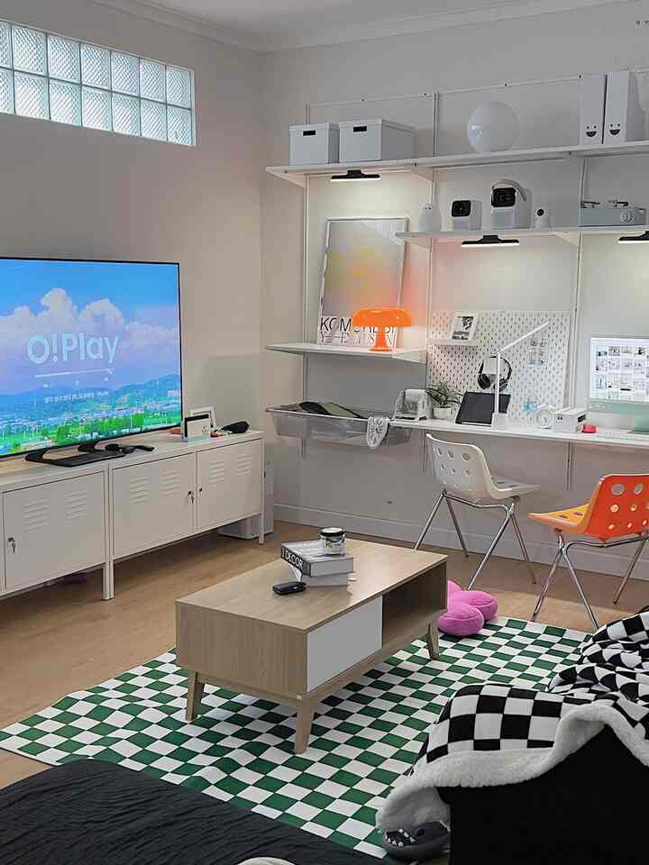 White-walled, wood-toned bedroom and home office featuring a minimalist Korean interior style with work desk, rug, and coffee table arranged in a cozy atmosphere
