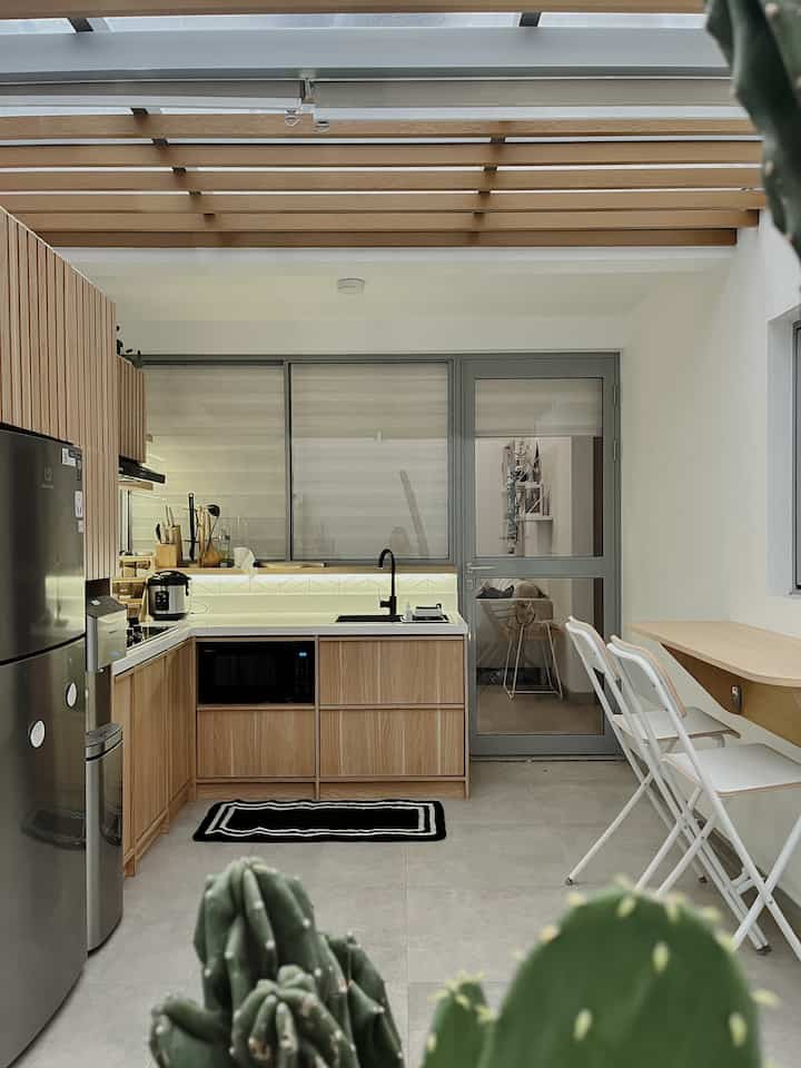 Natural wood tone and white semi-outdoor kitchen featuring pet presence with clean, modern atmosphere