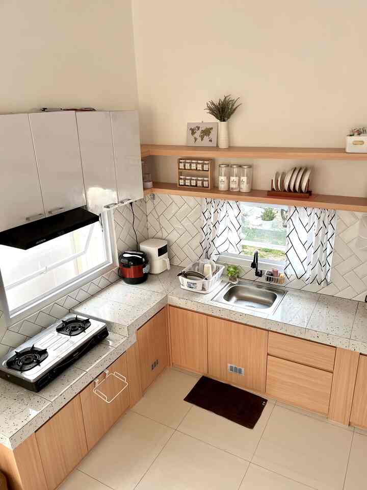 White walls and wood tone kitchen cabinets with open shelves and black-patterned curtains define a cozy small Japandi-style kitchen