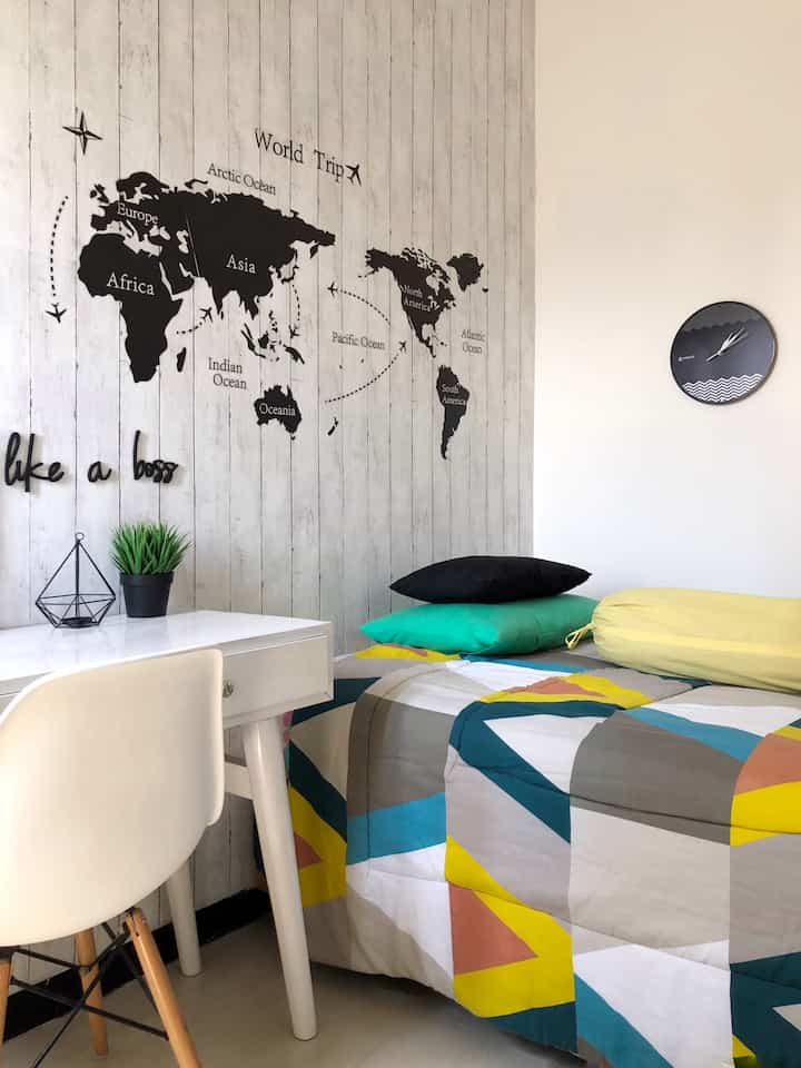 Monotone wall with white desk in a kids' room, featuring colorful bedding as a vibrant accent in a clean space