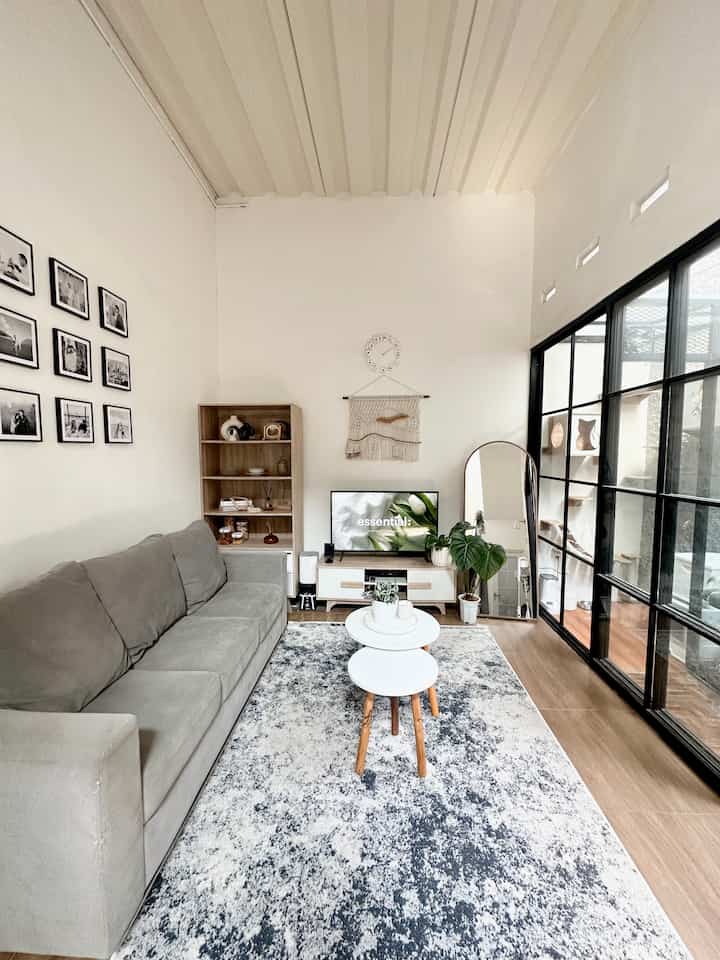 A compact living room in natural gray and wood tones, bright and neat with sliding glass door and large standing mirror