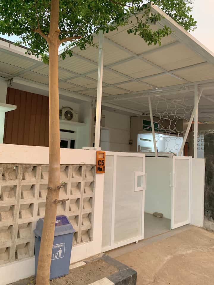 Clean white and gray toned entrance terrace featuring roster wall and tree for a cozy practical house facade