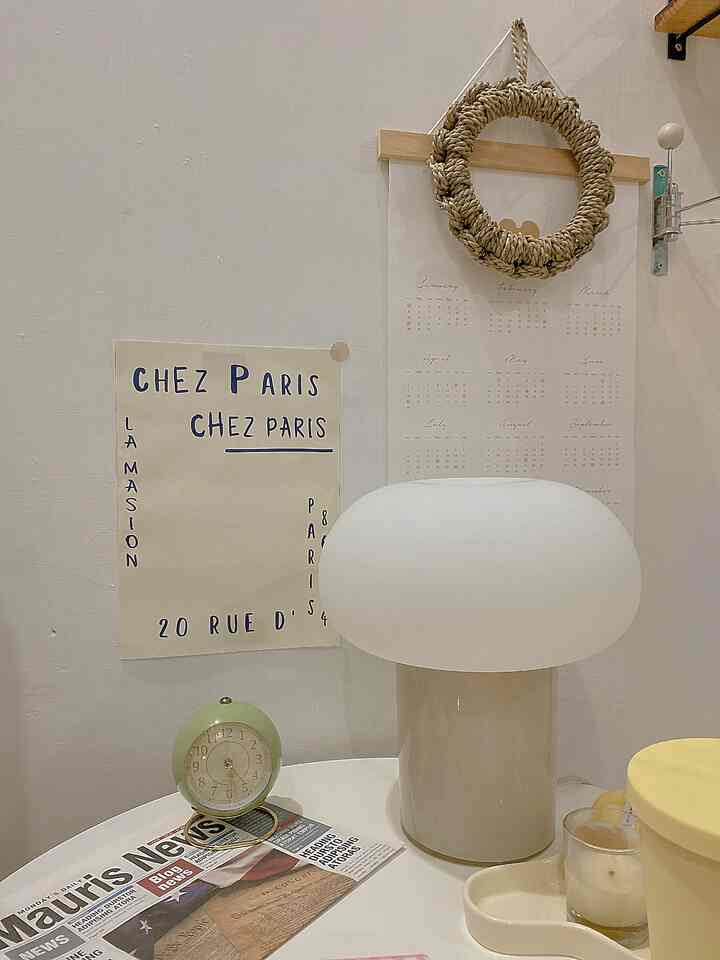 A cozy beige-toned small space featuring a table lamp, vintage clock, and rattan wreath creating natural warmth