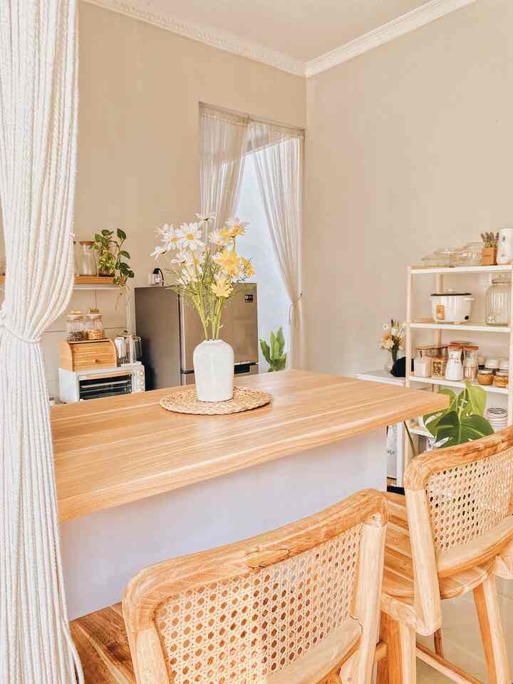 Bright white and wood tone Scandinavian kitchen with mini bar, vase of flowers, and plants creating a cozy atmosphere