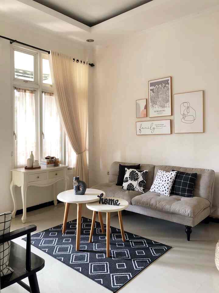 Beige and white toned living room featuring a beige sofa, round white side tables, and a black patterned carpet in a simple style