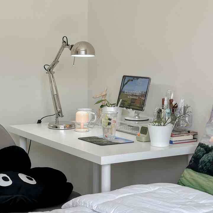 White-toned bedroom home office featuring a clean white desk and computer monitor in a simple setting