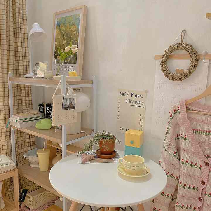 Beige and white toned natural style small room featuring round table with teacup and plant, French Country poster on wall