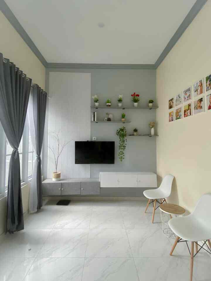 Bright and spacious gray and white toned living room featuring a wall-mounted TV and simple chairs