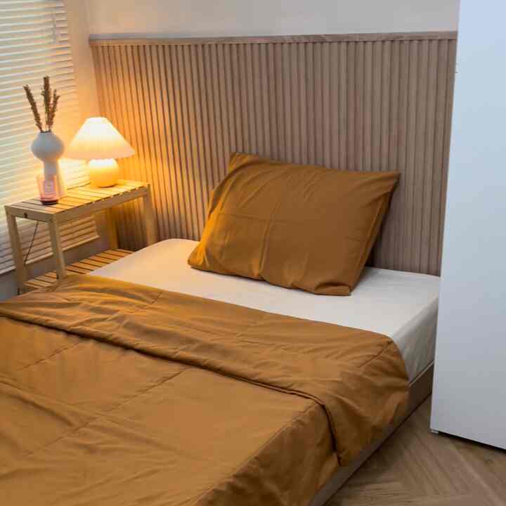 Warm wood tone bedroom featuring a bed, nightstand, and table lamp creating a cozy atmosphere