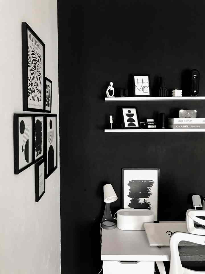 Monotone black and white home office space featuring simple picture frames, functional desk and office chair for a neat remote work environment