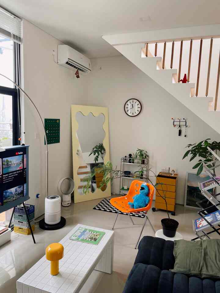 Bright toned Nordic living room featuring an orange chair, black sofa, and minimalist decor creating a cozy atmosphere
