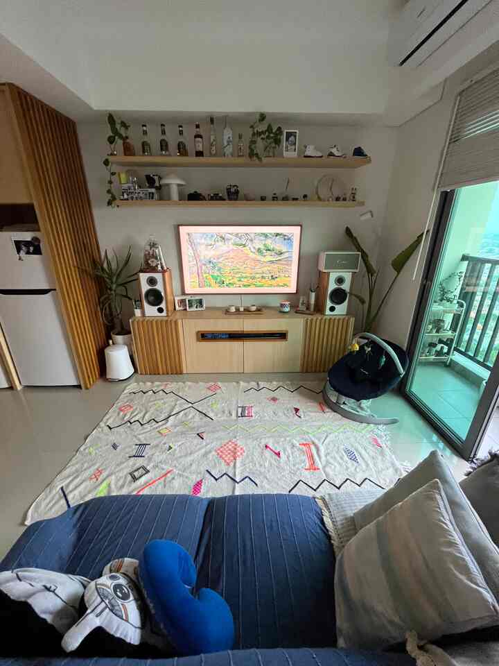 Modern living room with navy sofa and beige rug, featuring a TV stand, home bar shelves, and balcony view with cozy atmosphere