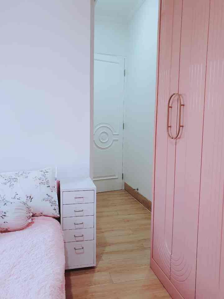 Pink and white toned bedroom featuring a bed, dresser, and wardrobe in a cozy small room