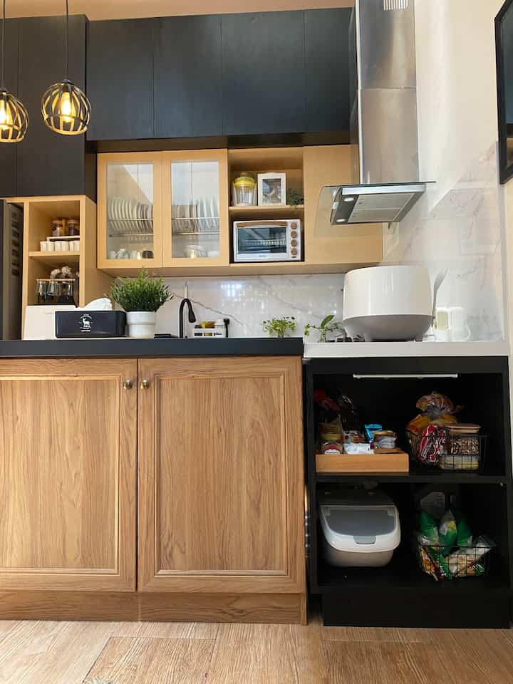 Black and wood-tone kitchen space featuring storage cabinets and marble backsplash in an industrial style interior