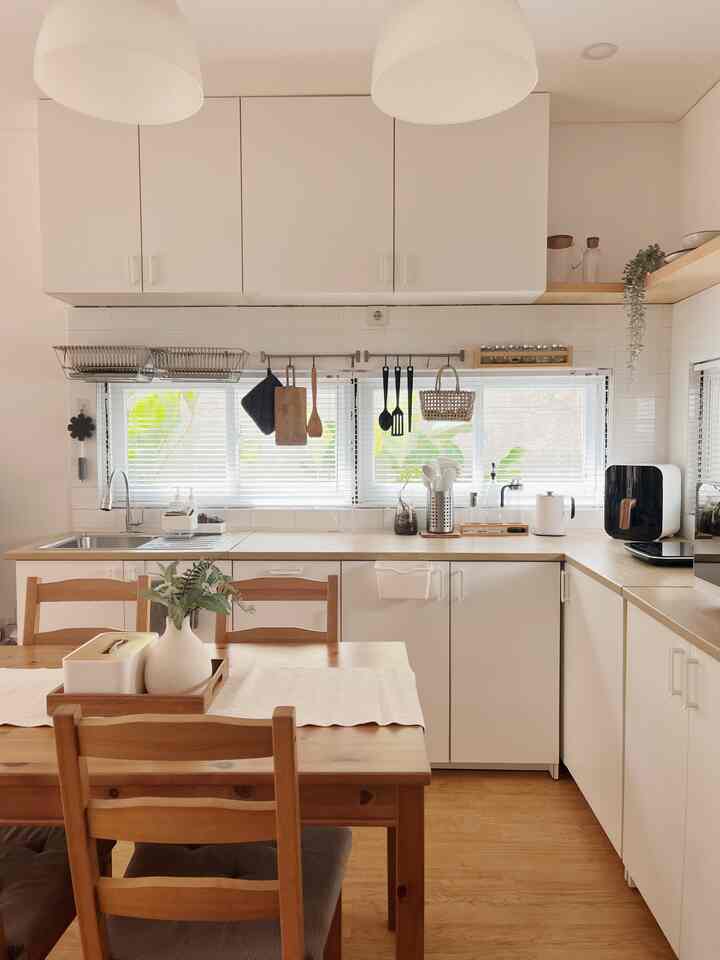 A white and wood tone kitchen space featuring wooden dining table and chairs with a natural cozy atmosphere.