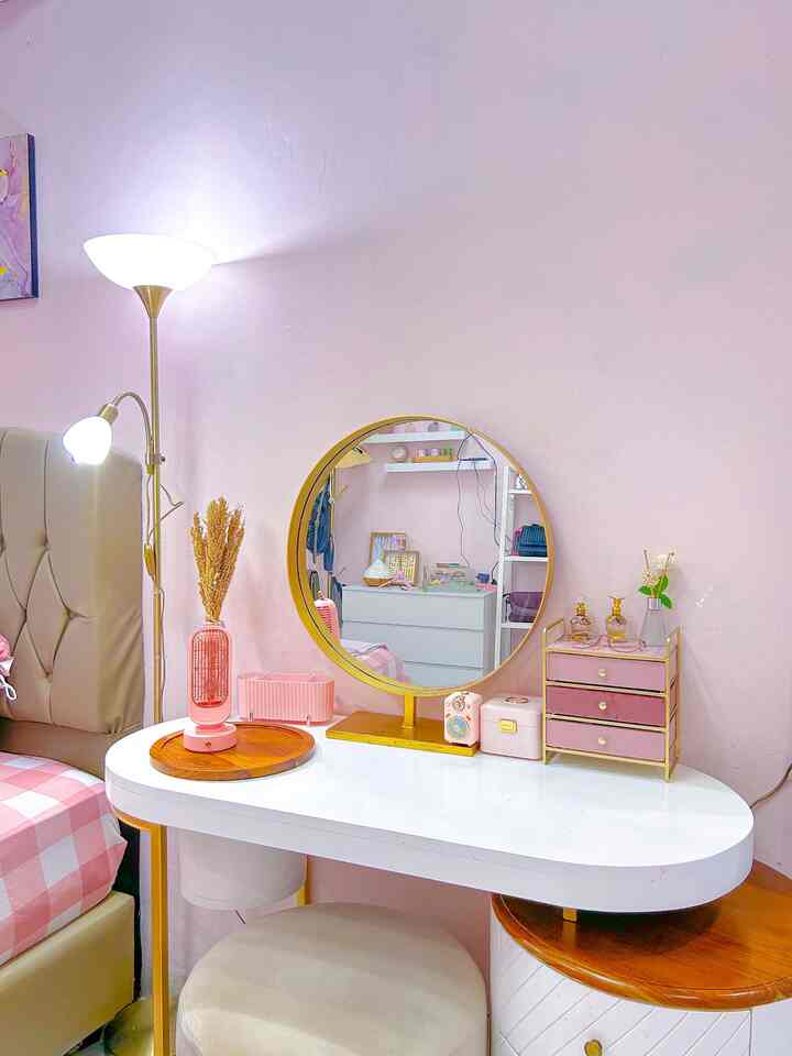 Pink-walled single household home office with white vanity, floor lamp and cozy decor for relaxing and working