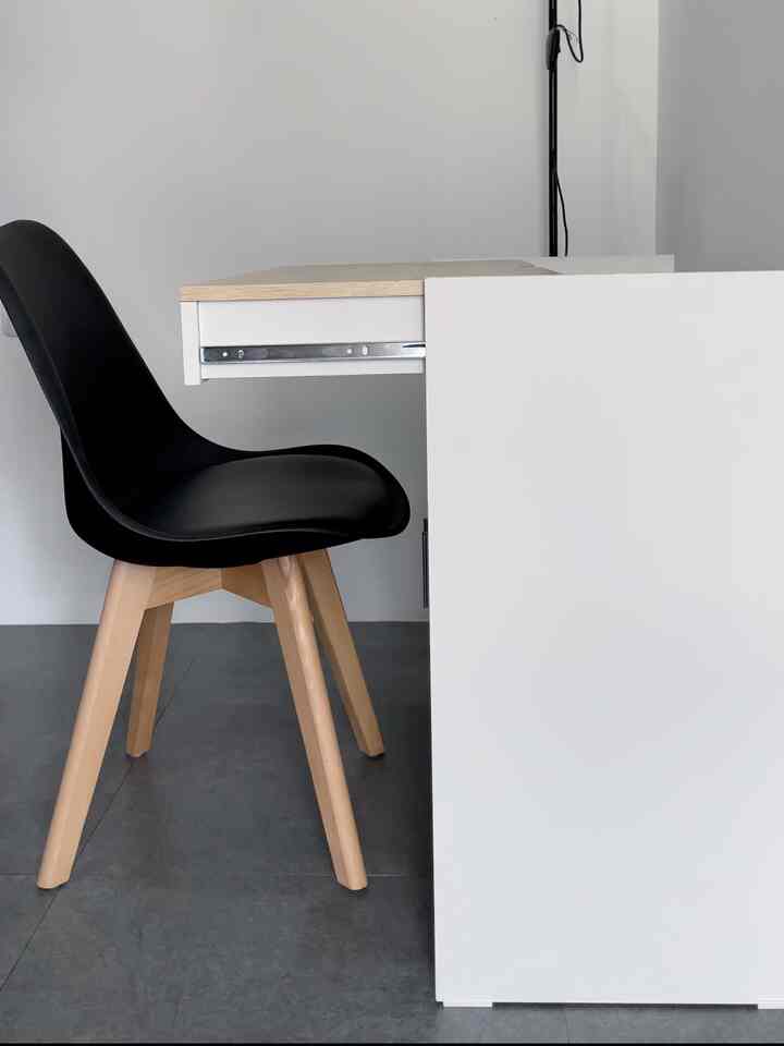 White and wood tone compact home office space featuring a black office chair and multifunctional desk