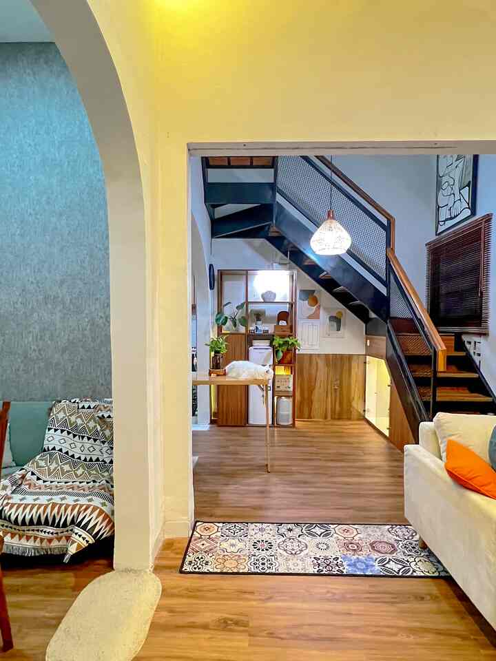 Warm wood tone Bohemian living room with archway, stairs, and plants creating an open cozy atmosphere
