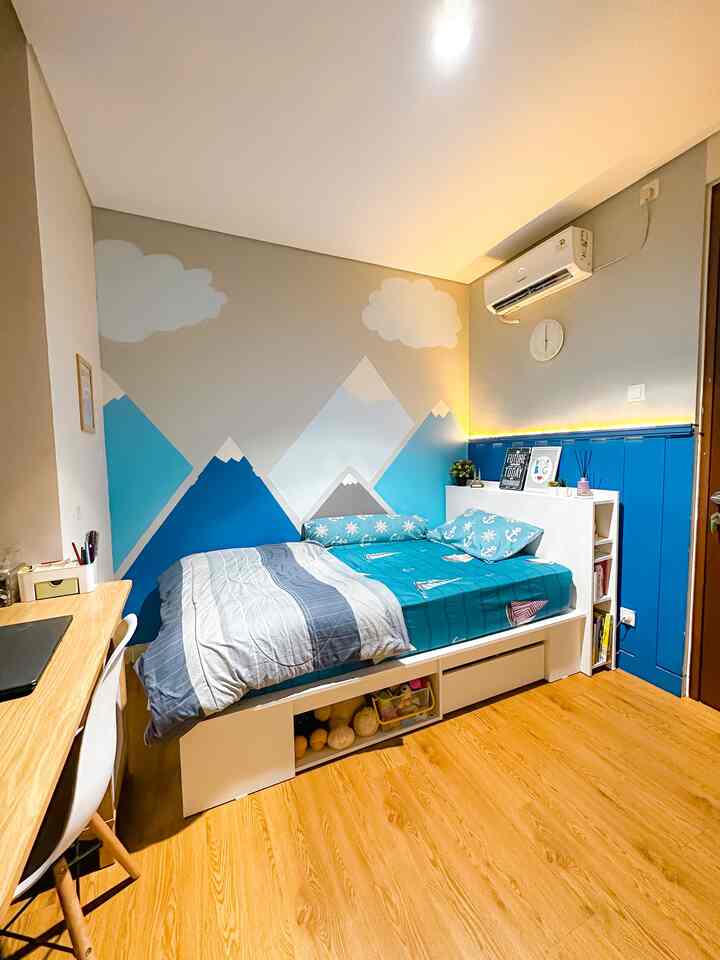 Natural wood tone floor and blue wall mural decorate a kids' bedroom featuring bed and desk with cozy atmosphere