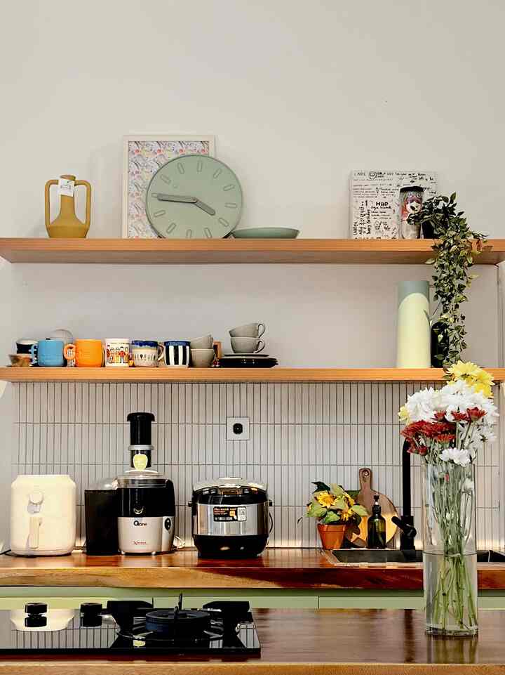 Natural tone kitchen with open shelving, assorted tableware and kitchen appliances, and a vase adding ambiance