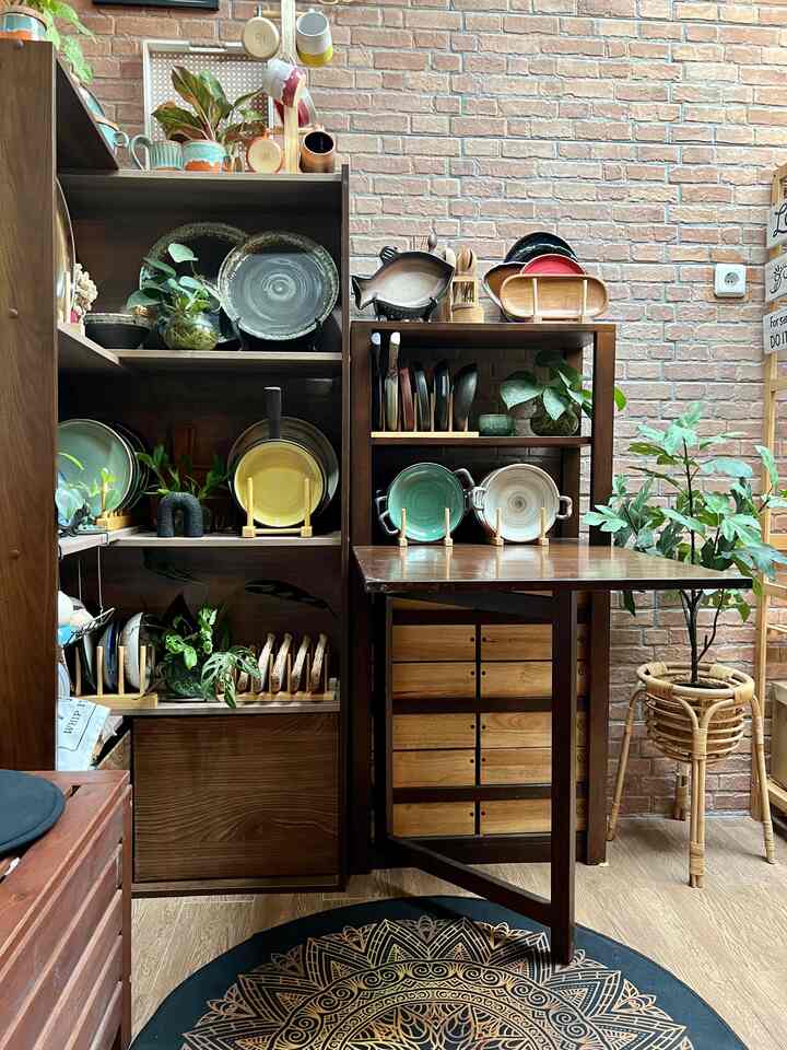 Meja lipat dengan rak ini, sebenernya aku custom setelah melihat contoh produk di sebuah market place. Aku pikir cocok banget buat di rumah yg spotnya memang terbilang sempit. Meja rak ini bisa di lipat saat tidak dibutuhkan sehingga menghemat space, sehingga leluasa untuk lalu lalang. Di bagian bawah rak, aku tambahkan beberapa laci sebagai storage.

Di sampingnya terdapat rak buku yg berwana coklat senada dengan tone warna sekitar, yang aku fungsikan untuk menyimpan koleksi keramikku. Warna asli rak ini sebenernya putih dan coklat krem, untuk lebih sesuai dan berbaur dengan warna sekitar, akhirnya diubah menjadi coklat tua. 

#customfurniture #DIYFurniture #personalizefurniture #uniquefurniture