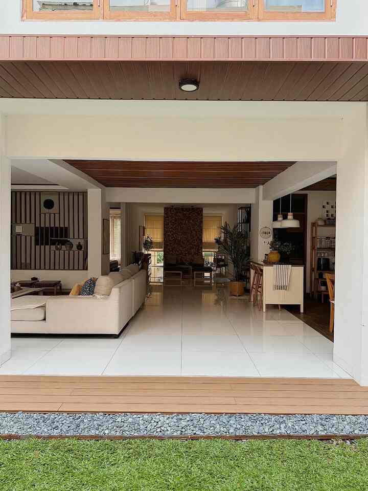 White and brown toned living room featuring a spacious sofa and wood ceiling, creating a natural modern atmosphere