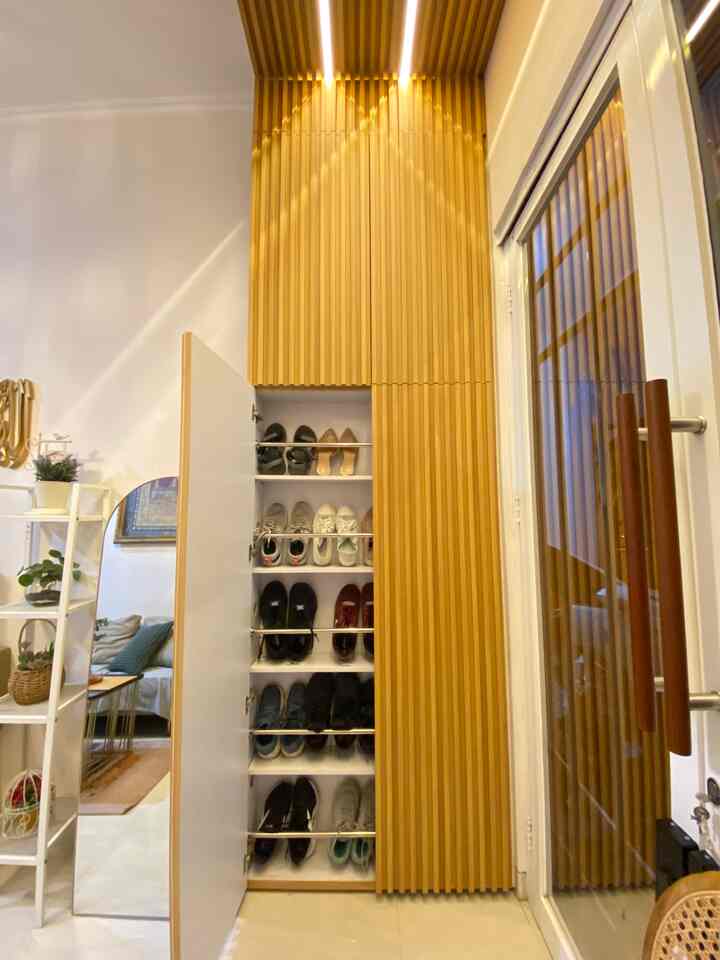 Minimal entrance and living room featuring white floors and walls with a wood-tone storage cabinet and ambient LED lighting