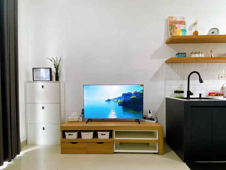 White and wood-tone living room and kitchen space featuring a TV stand and shoe cabinet in a clean modern interior