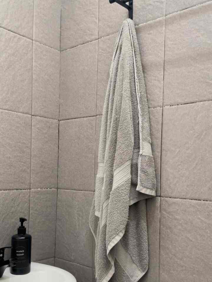 Gray monotone tiled walls with beige towel in a compact bathroom space