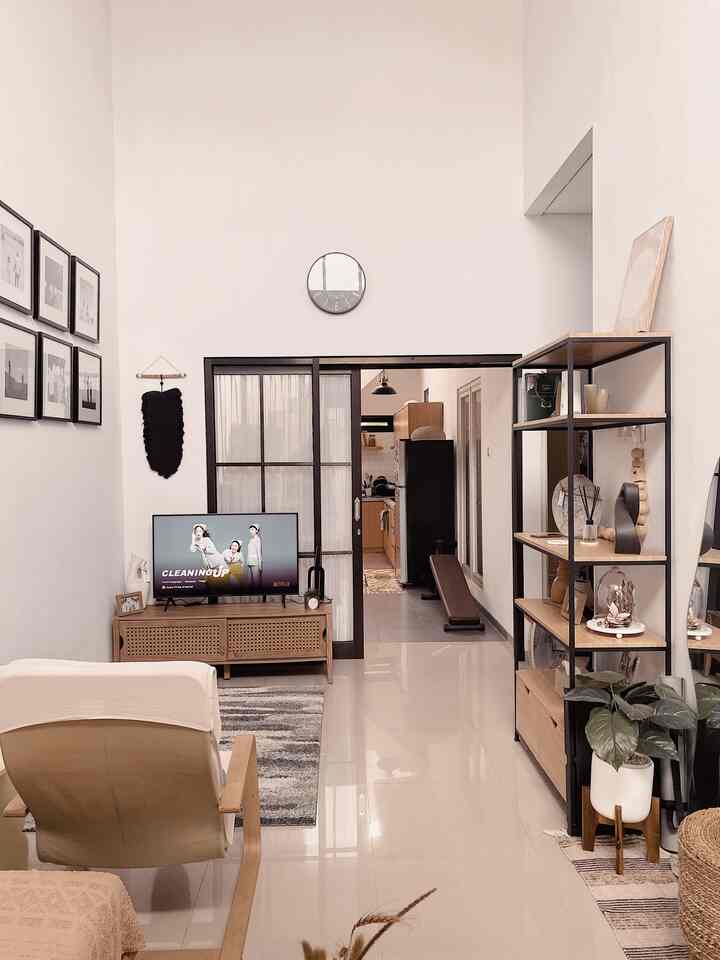 White and natural wood tone living room featuring beige-covered armchair and TV stand in simple modern style