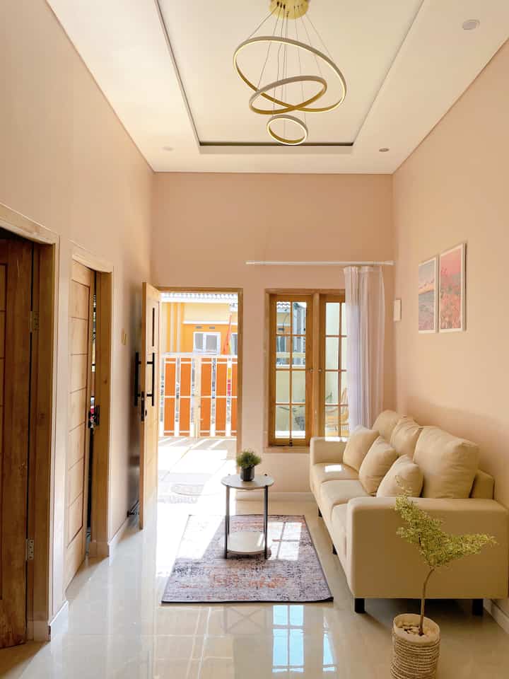 Pastel tone walls and natural wood blend in a narrow long living room featuring minimalist sofa and coffee table