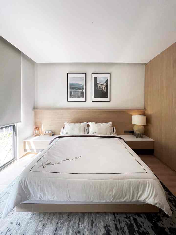 Natural-colored bedroom with wood tones, featuring a large bed and framed art, creating a simple and minimalist space
