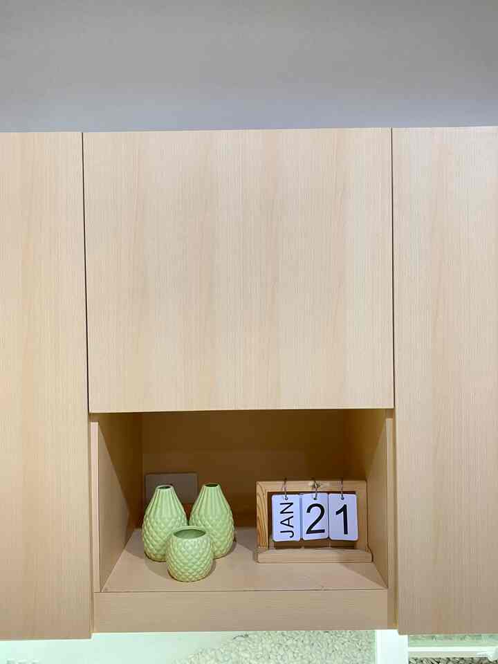 Natural tone wooden shelf featuring light green vases and a wooden frame calendar in a tidy kitchen corner