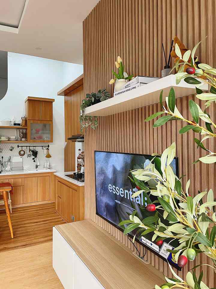 Warm wood tone and natural color Scandinavian style living room combined with kitchen, featuring TV and shelving