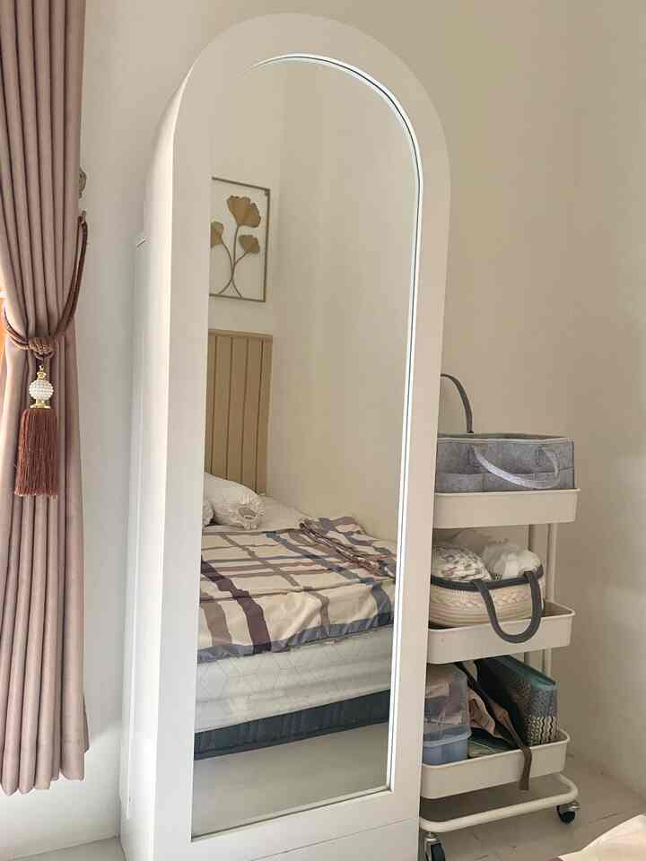 A cozy kids' room in white and beige tones featuring a full body mirror wardrobe with a multifunctional hijab cabinet and adjacent trolley storage for children's needs