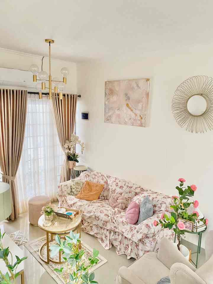Pastel tones and gold accents define this shabby chic living room, featuring a floral sofa and gold mirror creating a cozy atmosphere