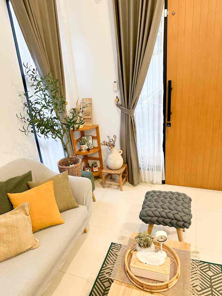 Wood tone and green accented living room featuring sofa and braided stool with cozy atmosphere