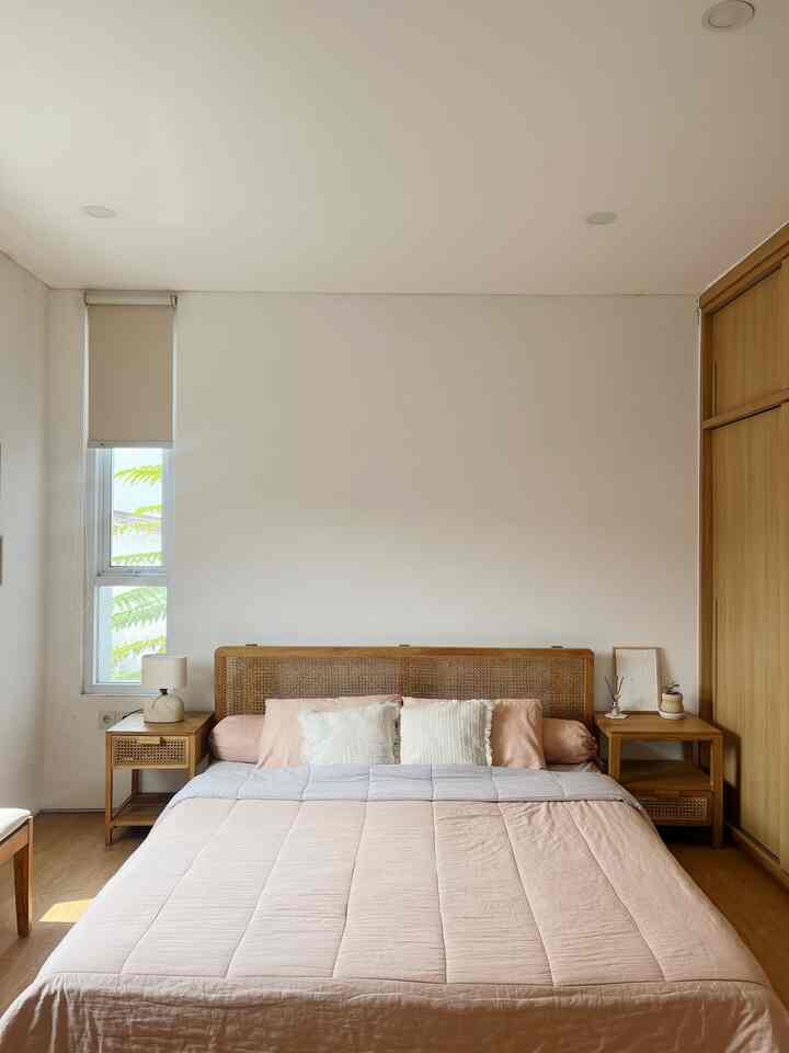 A simple bedroom featuring natural wood tones and beige bedding creating a calm atmosphere