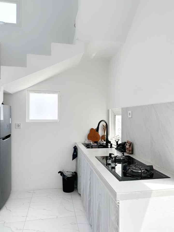 Minimalist Kitchen Area 
-

Dapur AngaHouse terletak dibawah tangga sehingga tersembunyi dari sudut pandang awal orang melihat ruangan, sengaja sekali kita membuat kitchen bertema serba putih agar setiap kali kotor bisa langsung dibersihkan tanpa ditunda. Top table dan backspace memakai materials granit berukuran 60x60 cm, tirai kita custom ala jejepangan dengan warna grey yang senada agar tidak terlalu mencolok. 

Element yang lebih ditonjolkan adalah sink cuci piring berwarna hitam dan kompor tanam juga berwarna hitam, Tempat sampah juga hitam materials besi, Lemari Pendingin warna dark grey selain itu berwarna putih 

#kitchenstyling #kitchendecorideas #kitchenmakeover #rumah #minimalist #bauhaus #homedecor #deco #homestagram #interiorrumah #angkahouse #72sqm 
