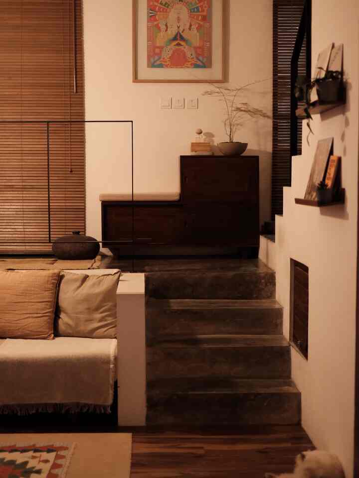 Warm wood tones and natural colors define the living room featuring a sofa and wall art creating a cozy atmosphere