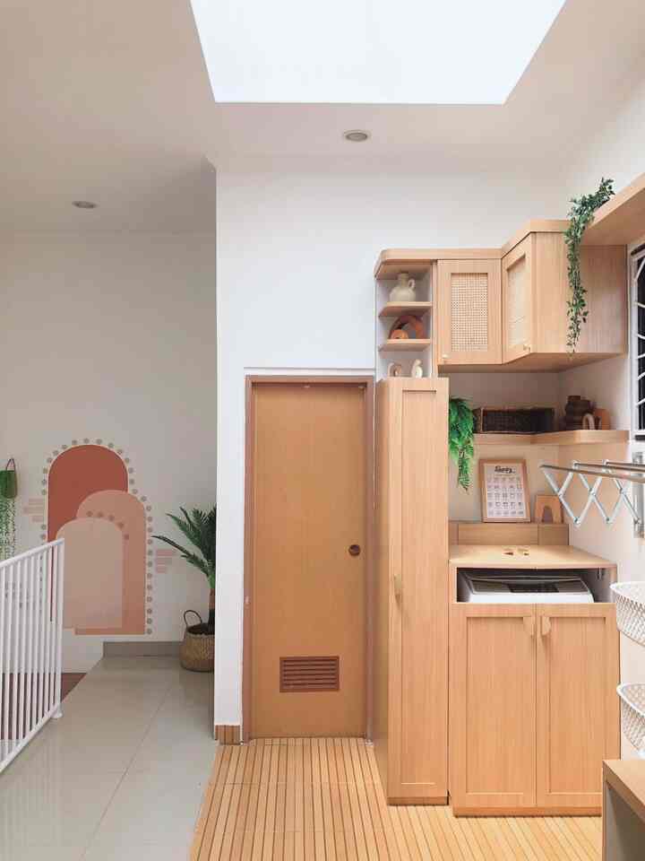 Natural toned long narrow room featuring wooden storage cabinetry beside a central door with a clean atmosphere