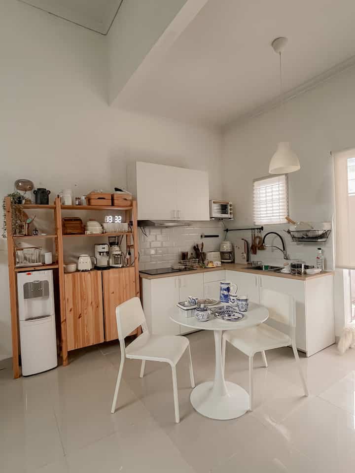 White and wood tone kitchen featuring a round dining table and pendant light creating a cozy atmosphere