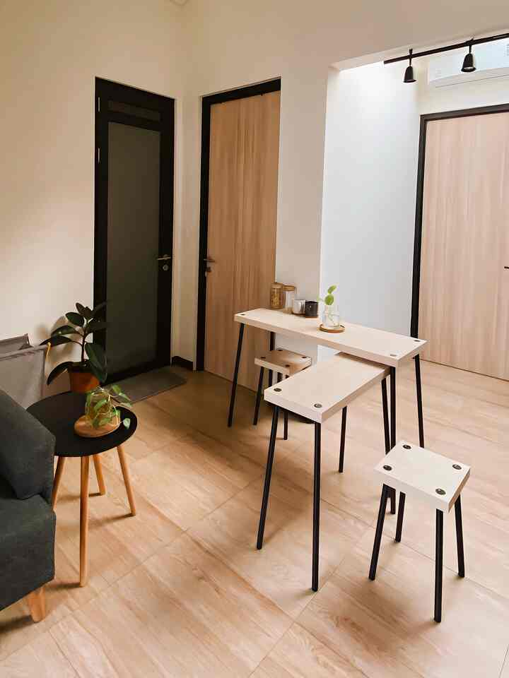 Simple dining room with natural wood tone flooring and white table set, partial view of a sofa
