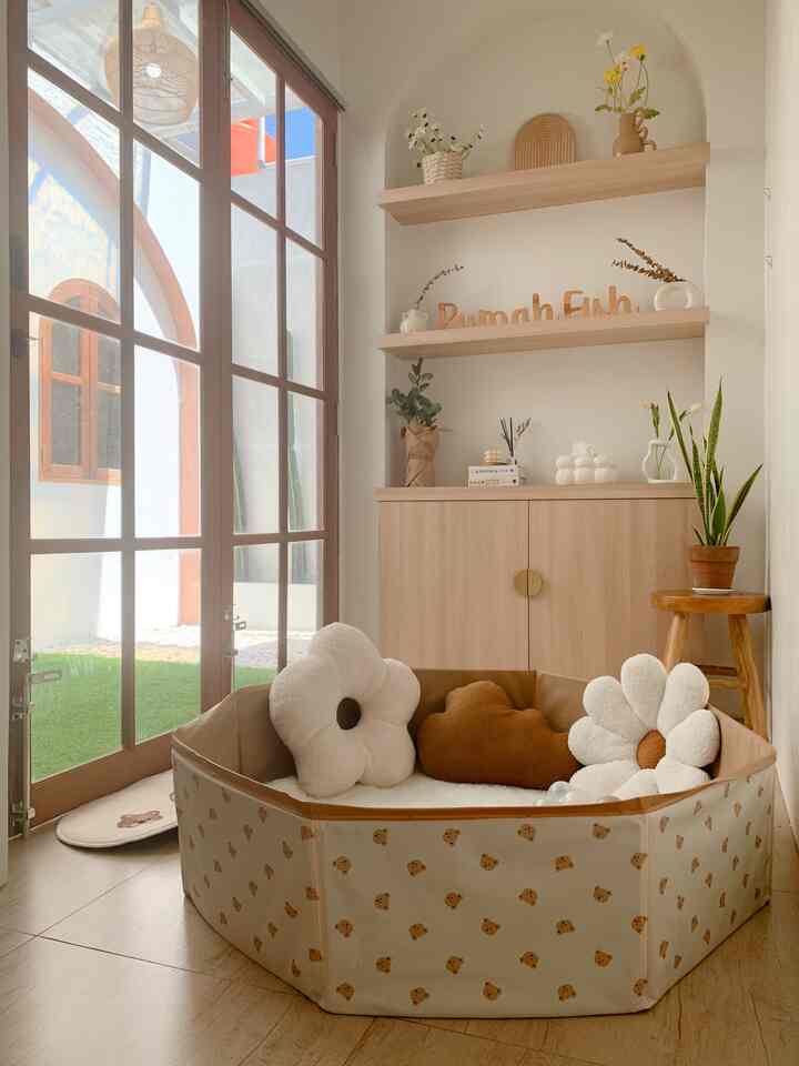 Beige and wood-tone kids' room featuring flower-shaped cushions and a baby playpen in a warm, cozy space