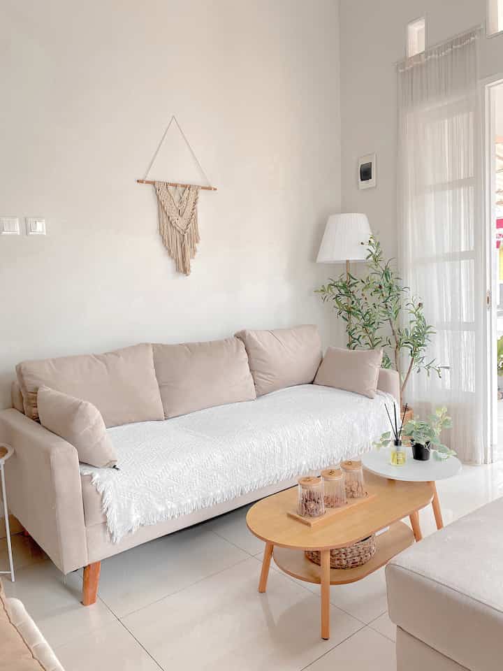 Natural color and white toned living room featuring beige sofa and wood tone coffee table with a minimal and cozy atmosphere