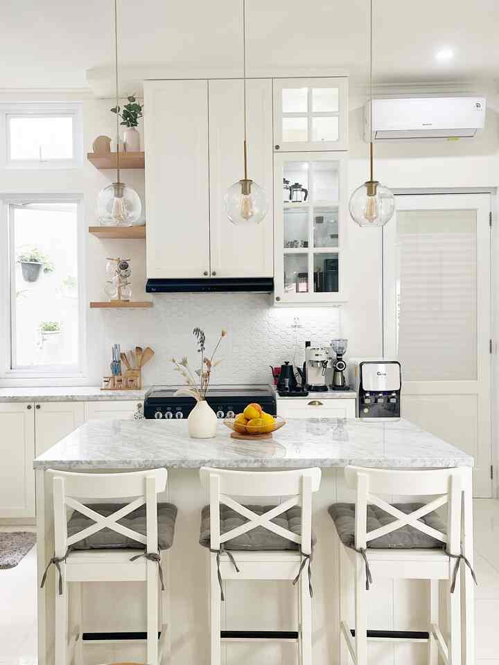 Bright modern kitchen in white tones featuring an island dining table with chairs neatly arranged